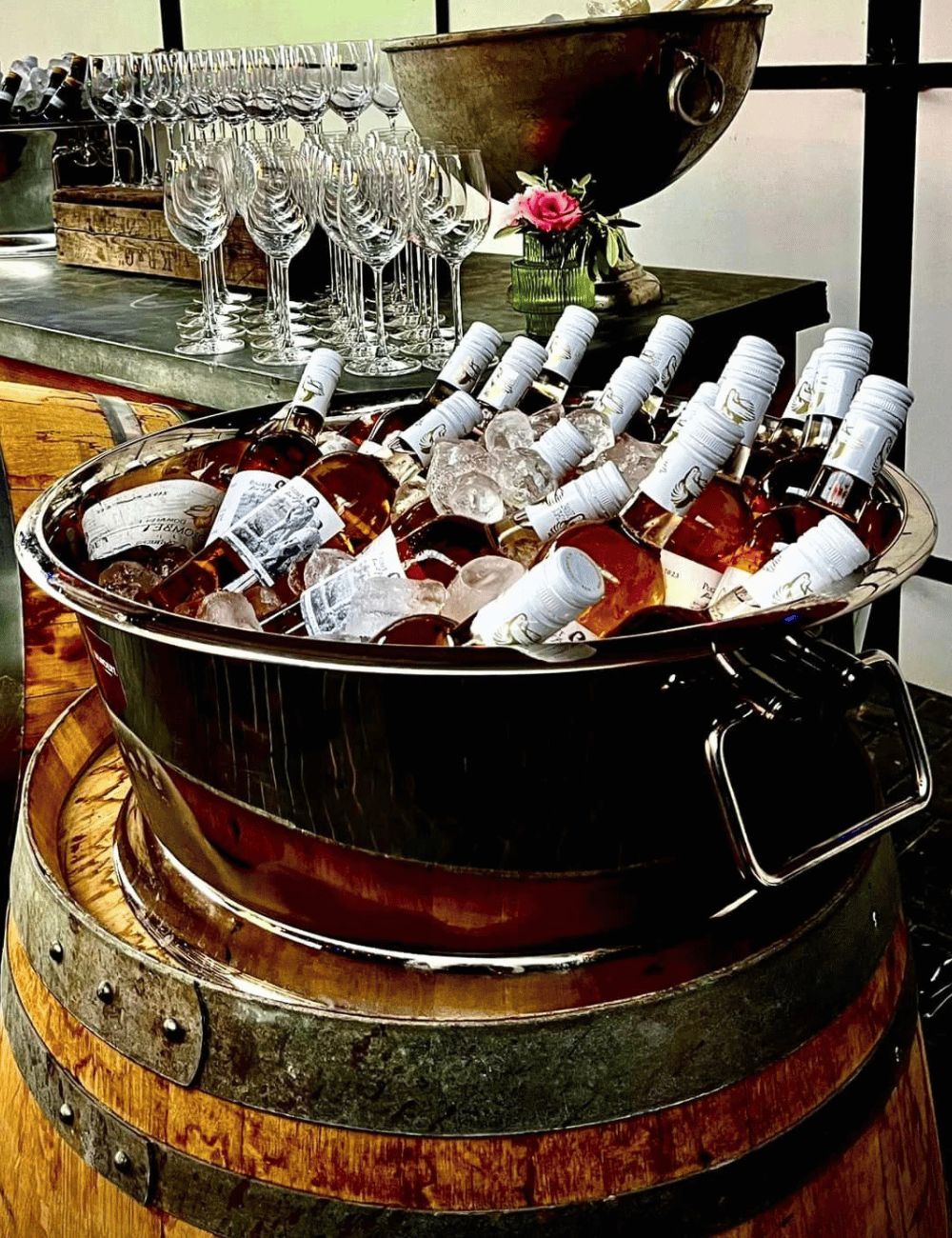 Portofino bowl filled with rosé bottles on ice, set on a wine barrel