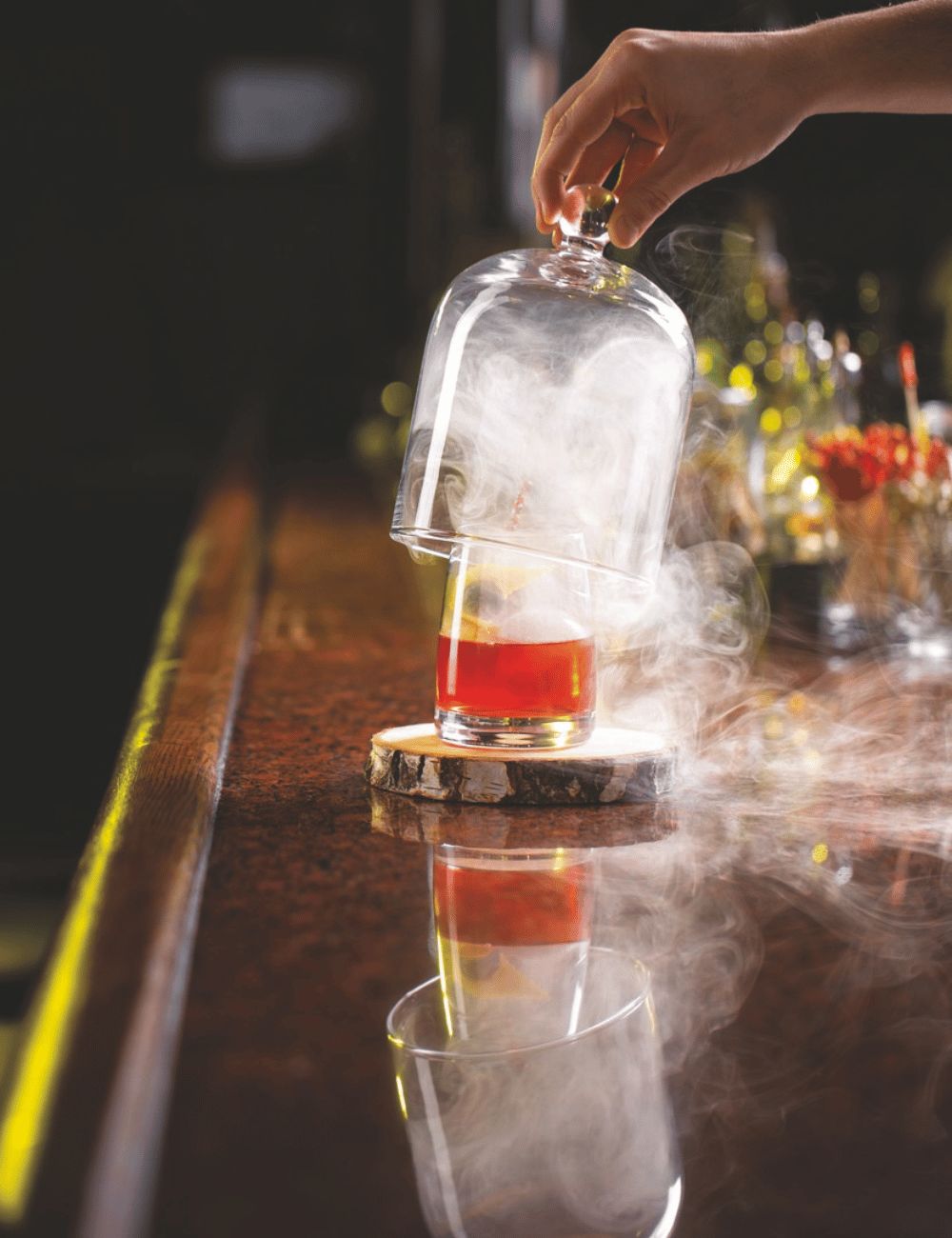 Smoke-filled glass cloche lifted above a cocktail