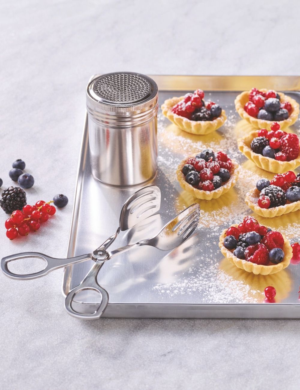 PADERNO Living stainless steel pastry tongs beside berry tartlets on a stainless steel tray
