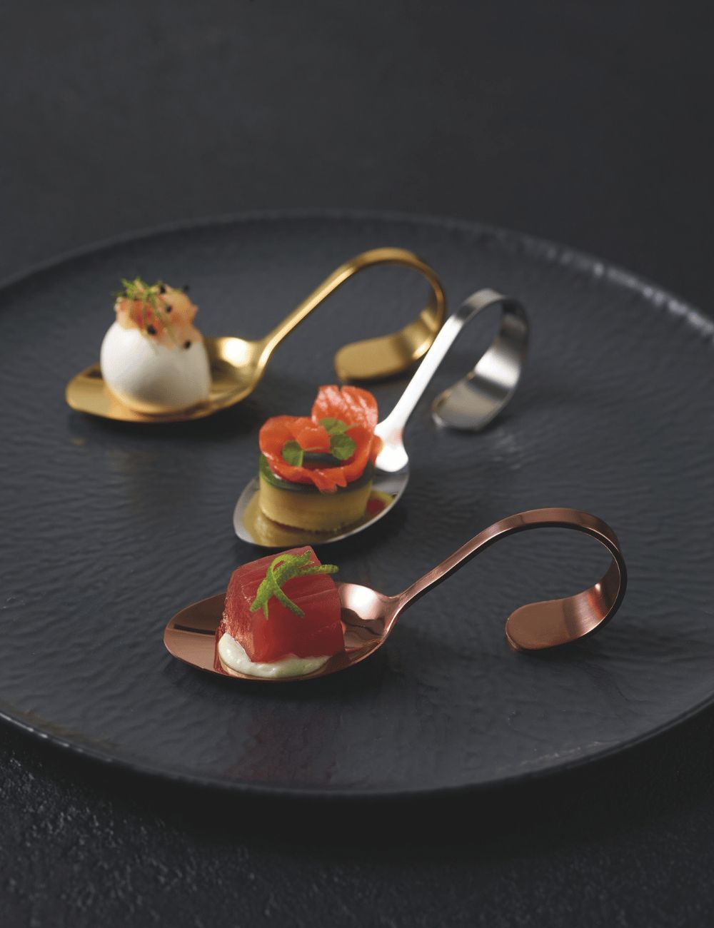 PADERNO silver, copper and gold Gourmet amuse-bouche spoons with savoury bites on a black plate
